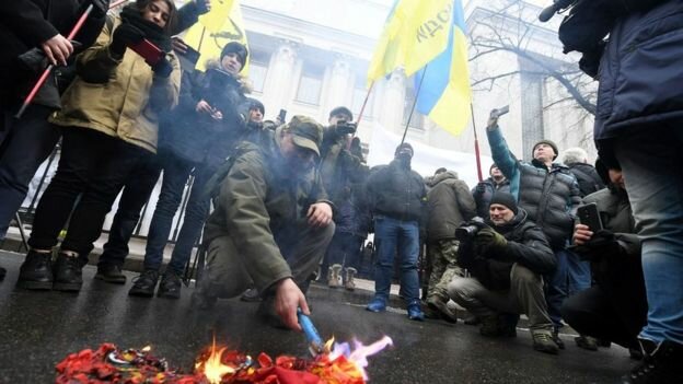 Ukrainian activists burn the Russian flag and St George ribbons outside parliament in Kiev / bbc.com